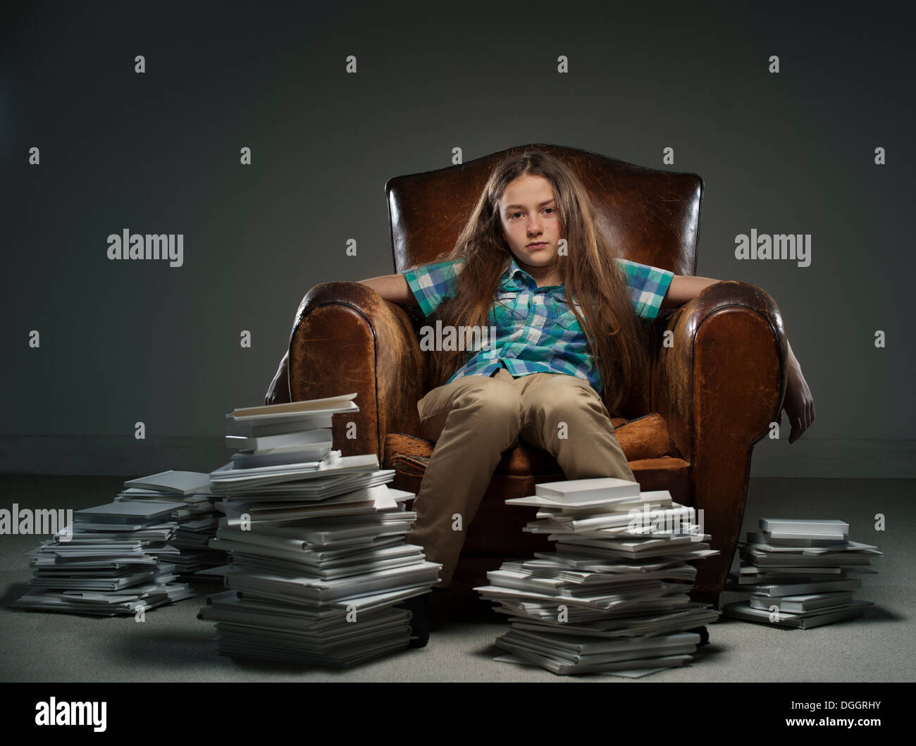 Girl sitting in leather armchair with piles of books Stock Photo - Alamy
