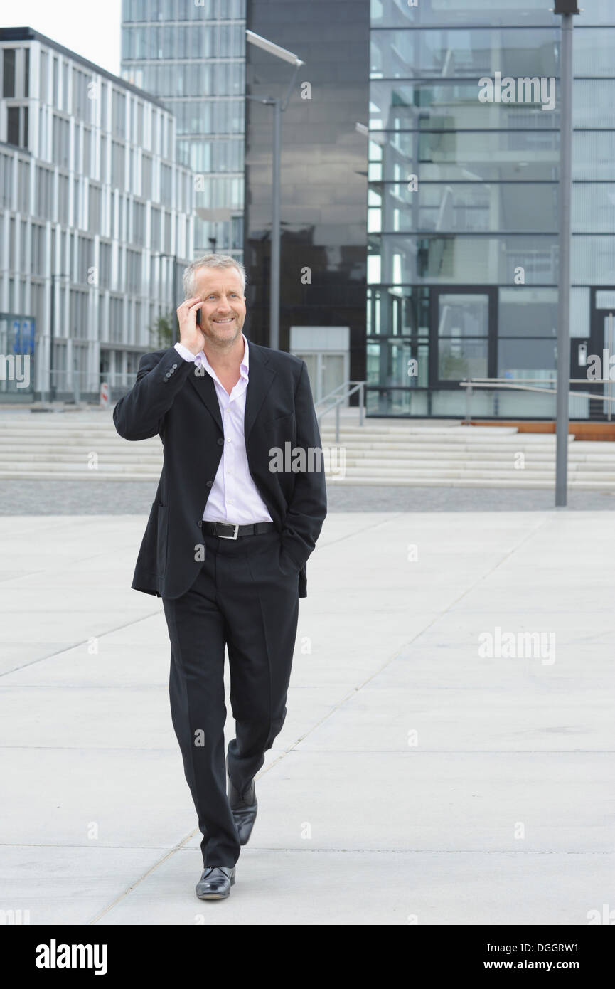 Mature man walking in financial district and using cellphone Stock Photo
