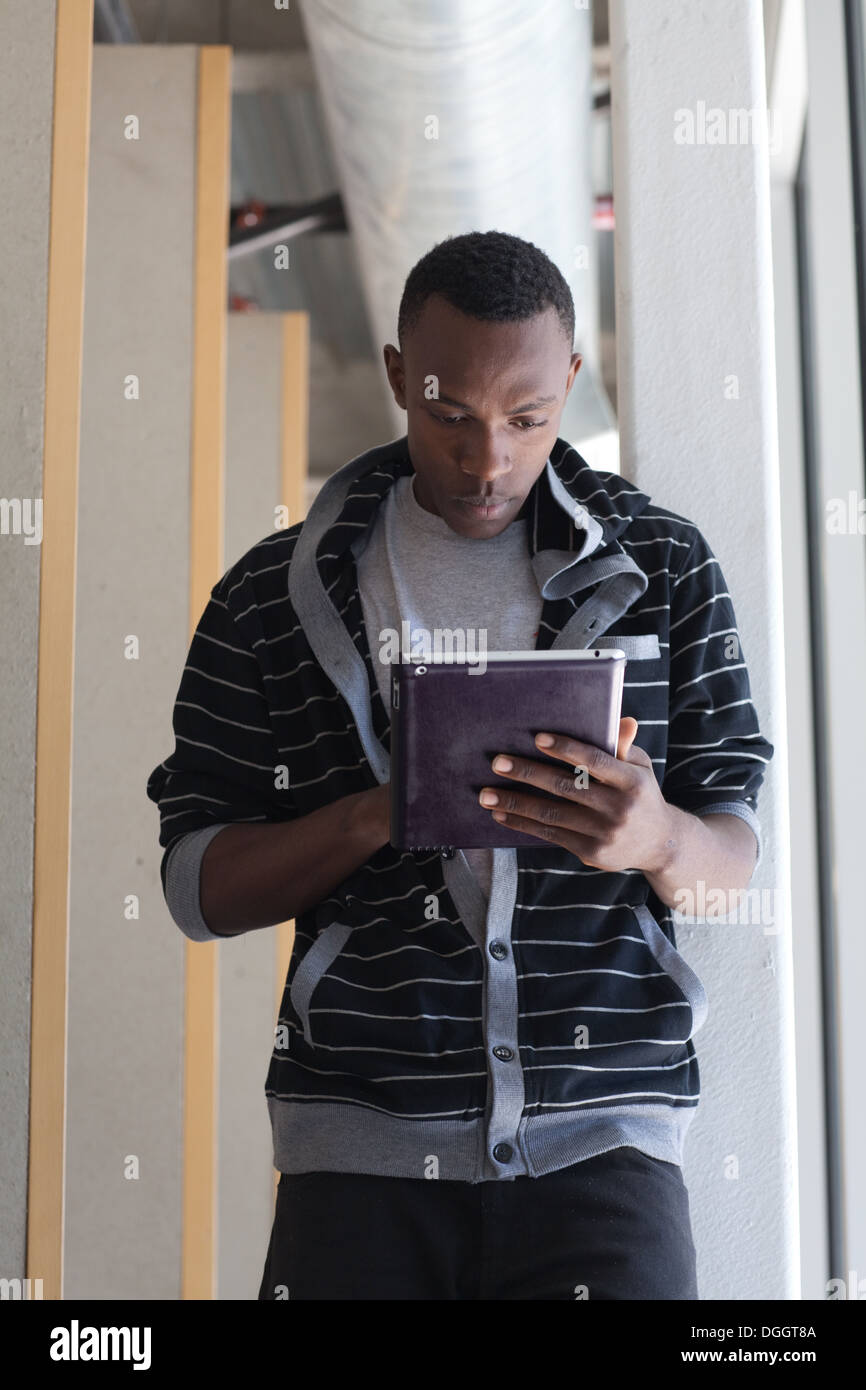 Eighteen year old college student using an ipad in a hallway. Stock Photo