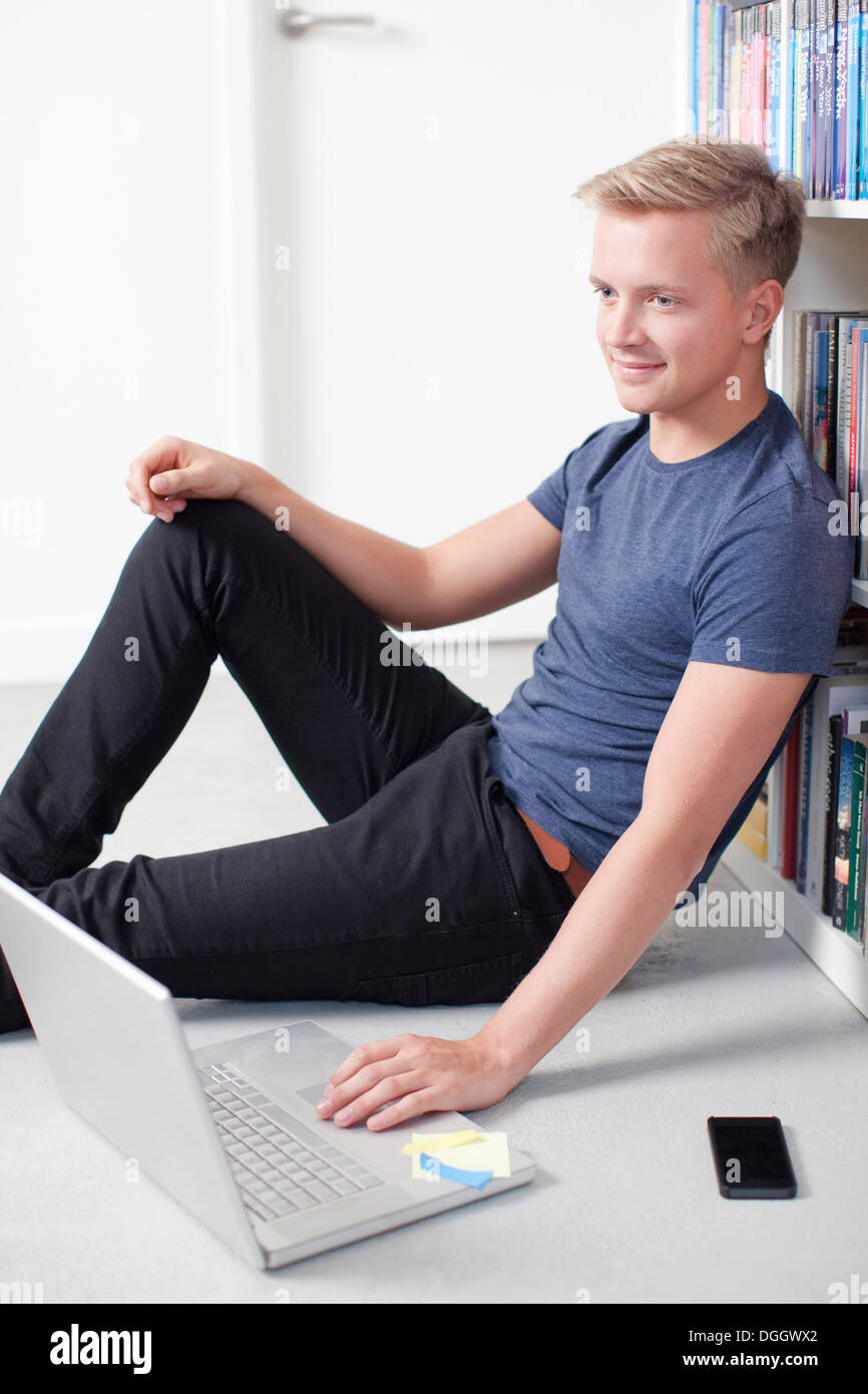 Young man sitting on floor using laptop Stock Photo