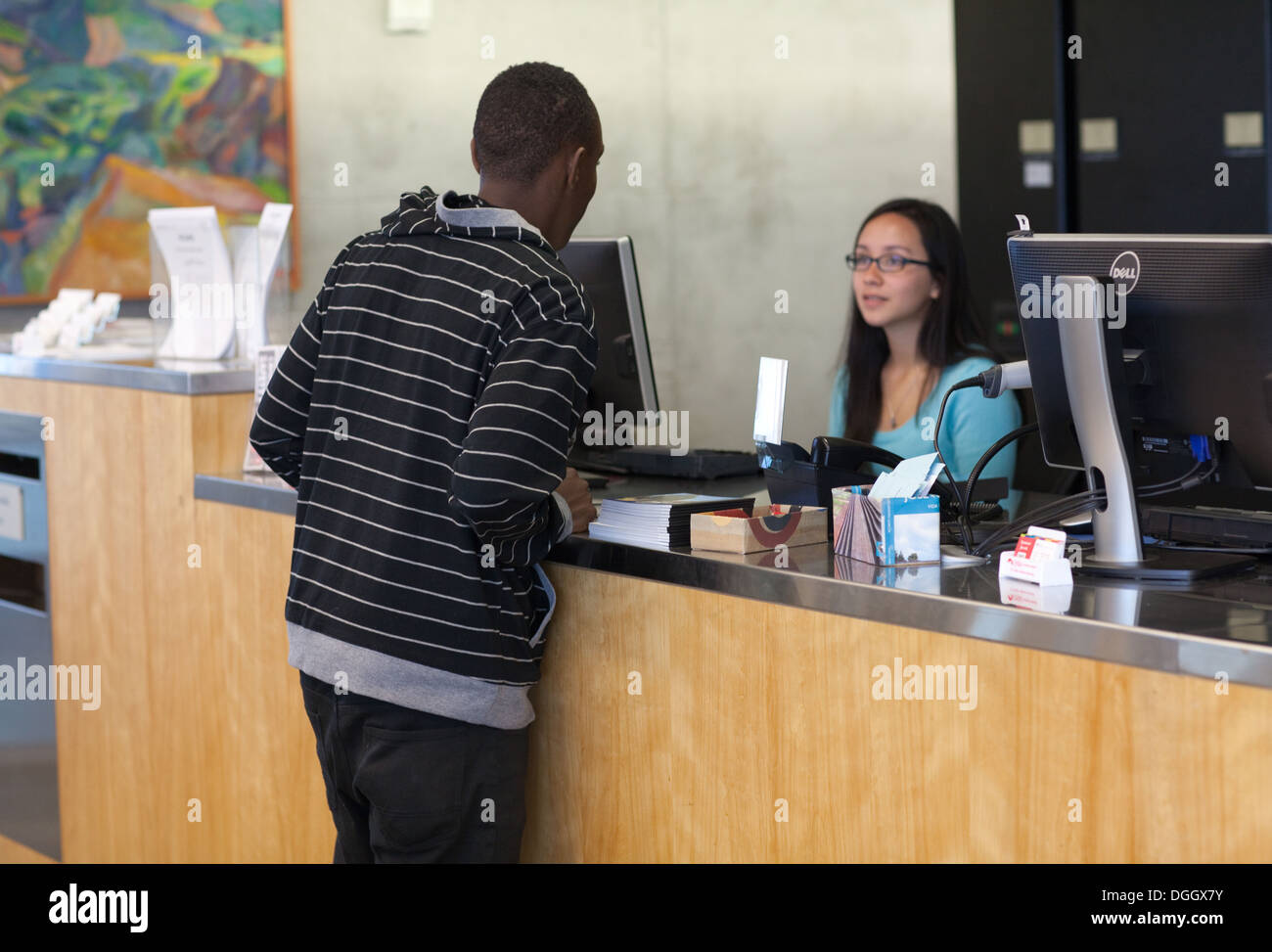 African teenage student asks reference librarian a question. Stock Photo