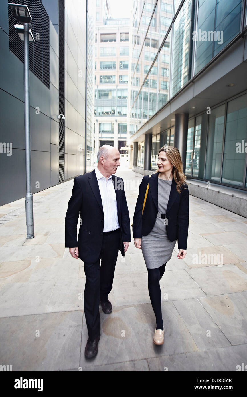 Businessman and businesswoman walking past office buildings Stock Photo