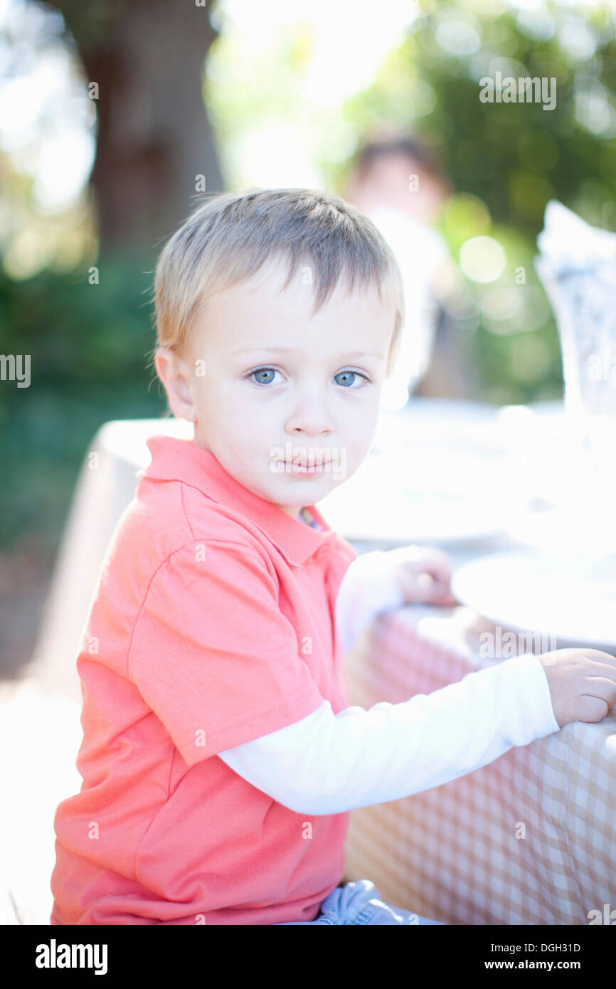 Little boy sitting at table outdoors Stock Photo Alamy