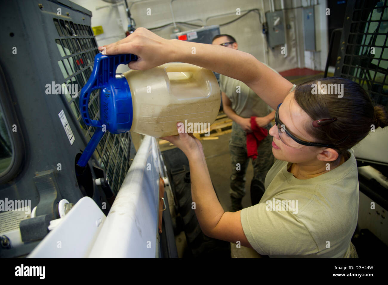 Airman 1st Class Johanna Desimone, 5th Logistics Readiness Squadron vehicle maintainer, pours fluid into a loader after checking the fluid level at Minot Air Force Base, N.D., Oct. 16, 2013. The 5th LRS vehicle maintenance flight repairs and maintains var Stock Photo