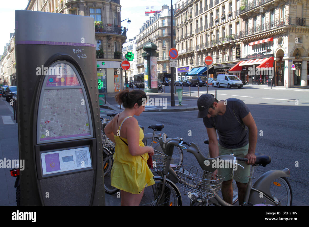 Paris France,2nd arrondissement,Rue des Filles Saint-Thomas,Velib bike share system,man men male,adult,adults,woman female women,couple,taking bicycle Stock Photo