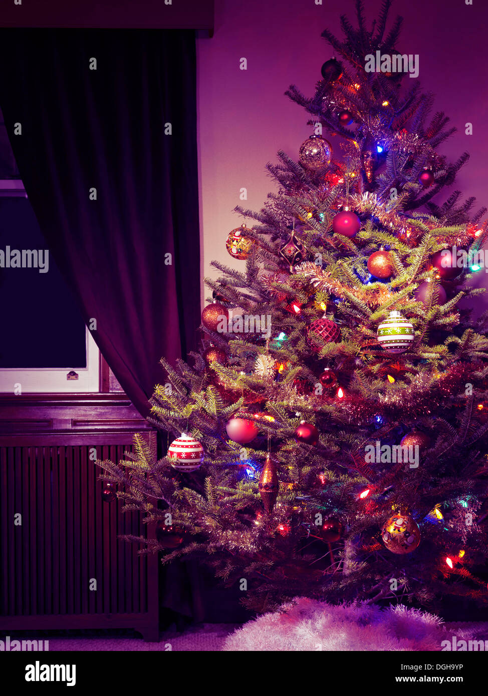 Decorated Christmas tree indoors at night with its lights on Stock