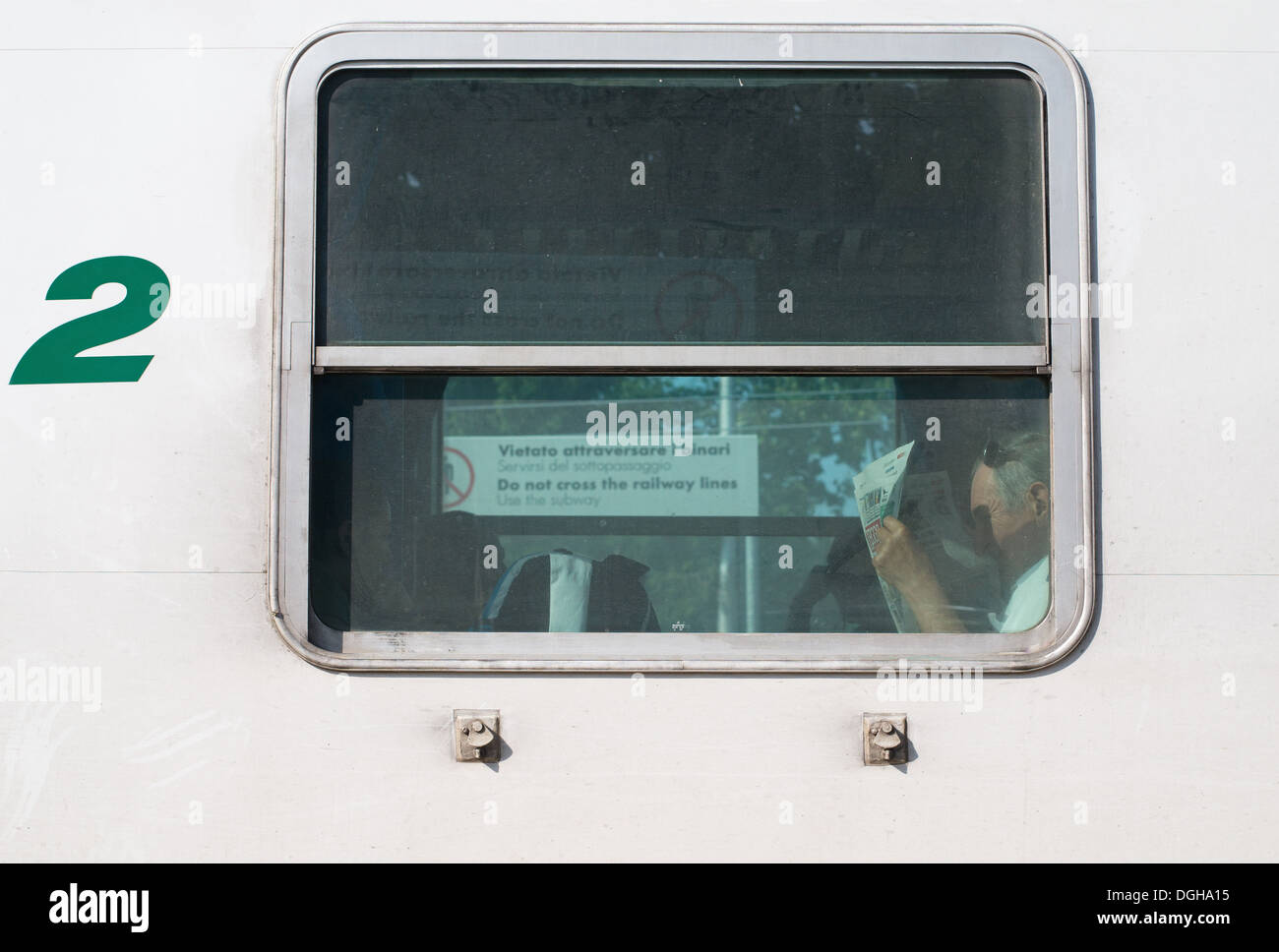 Man reading newspaper in the window of a Trenitalia railway carriage, Italy, Europe Stock Photo