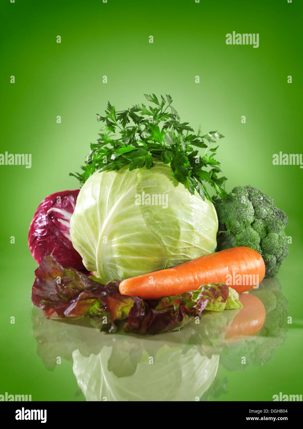 Colorful vegetable healthy food still life, cabbage and greens on green background Stock Photo