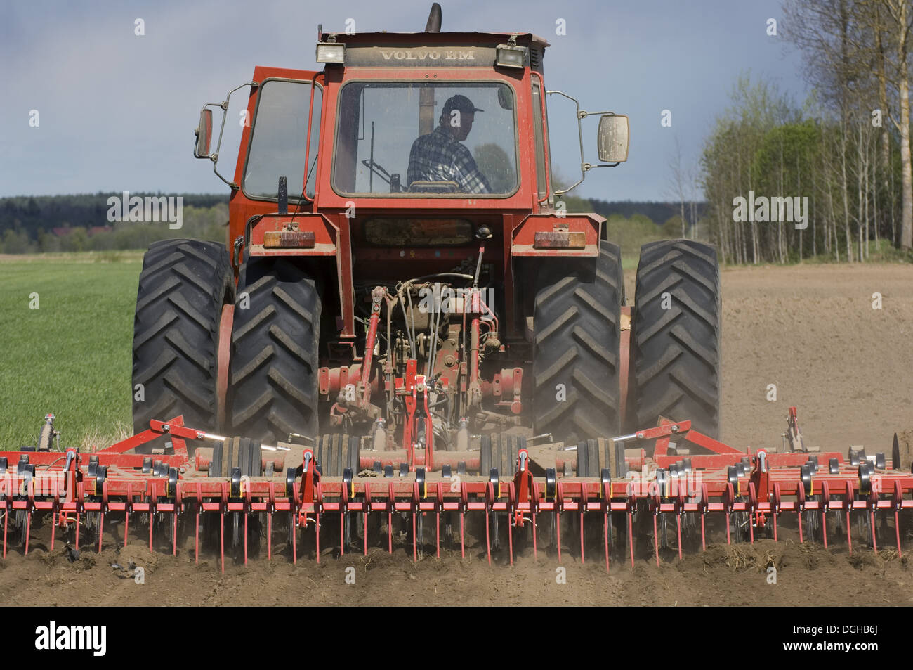 Volvo tractor pulling harrows, cultivating arable field, Sweden Stock Photo