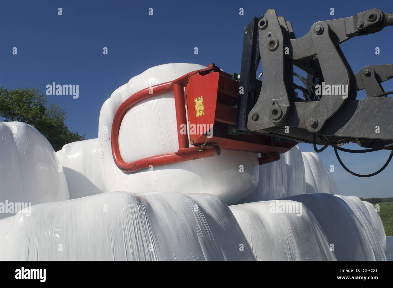 Plastic wrapped round silage bales, stacked onto pile with mechanical loader, Sweden Stock Photo