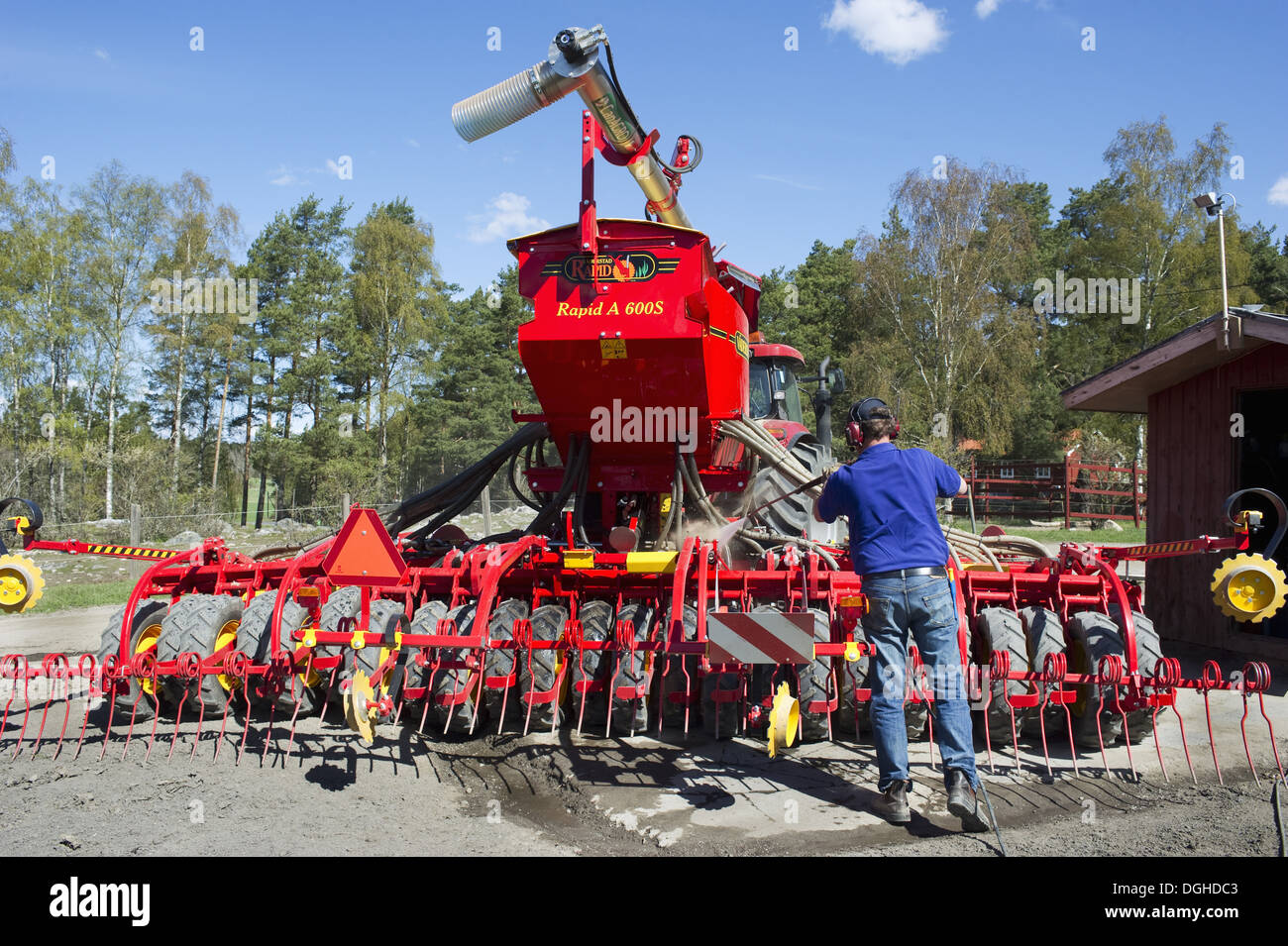 Farmer washing Vaderstad Rapid A 600S seed drill with pressure washer, Upplands Vasby, Sweden, may Stock Photo