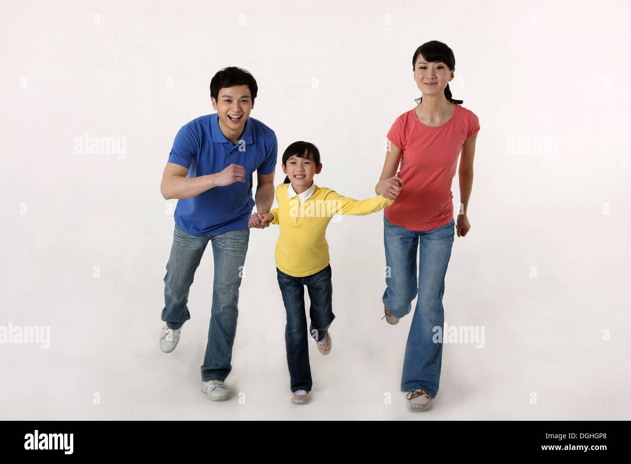 East Asian family with one child running hand in hand, smiling, looking at camera Stock Photo