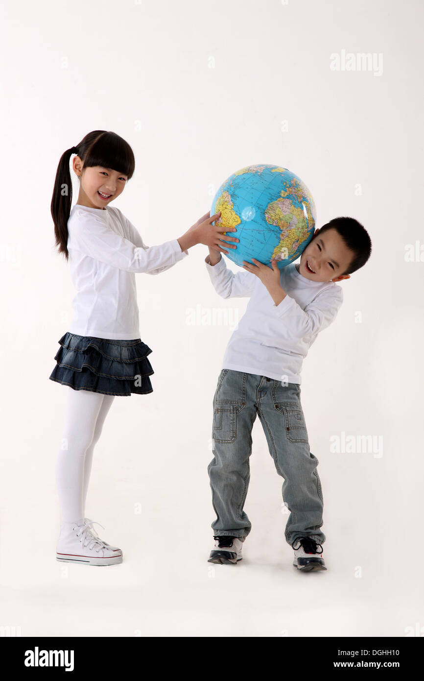 East Asian boy and girl carrying a globe on the shoulders, smiling, looking at the camera Stock Photo