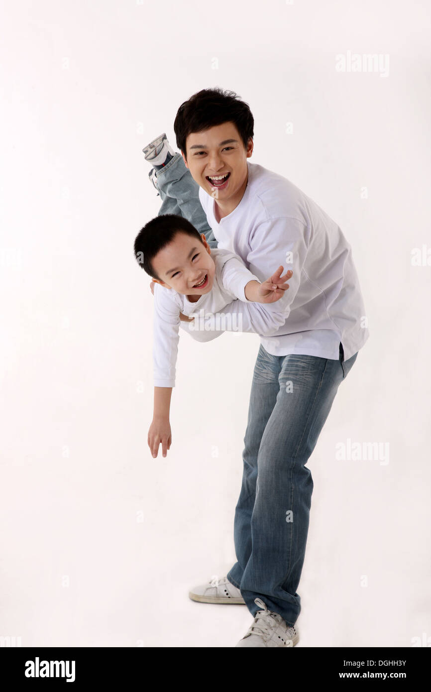 East Asian father holding son up in the air, smiling Stock Photo