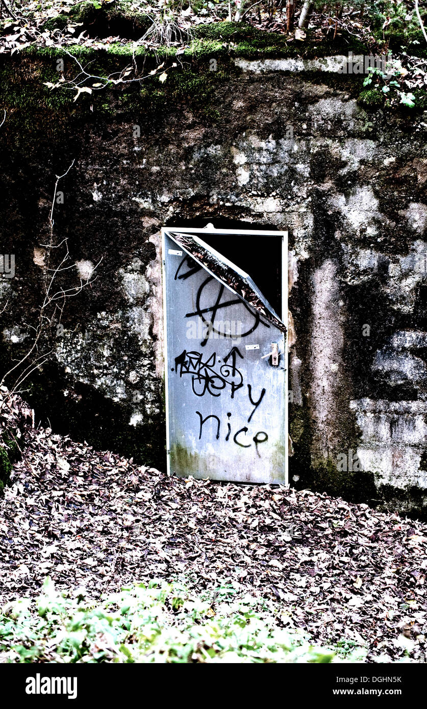 Bent old metal door with graffiti in weathered wall Stock Photo