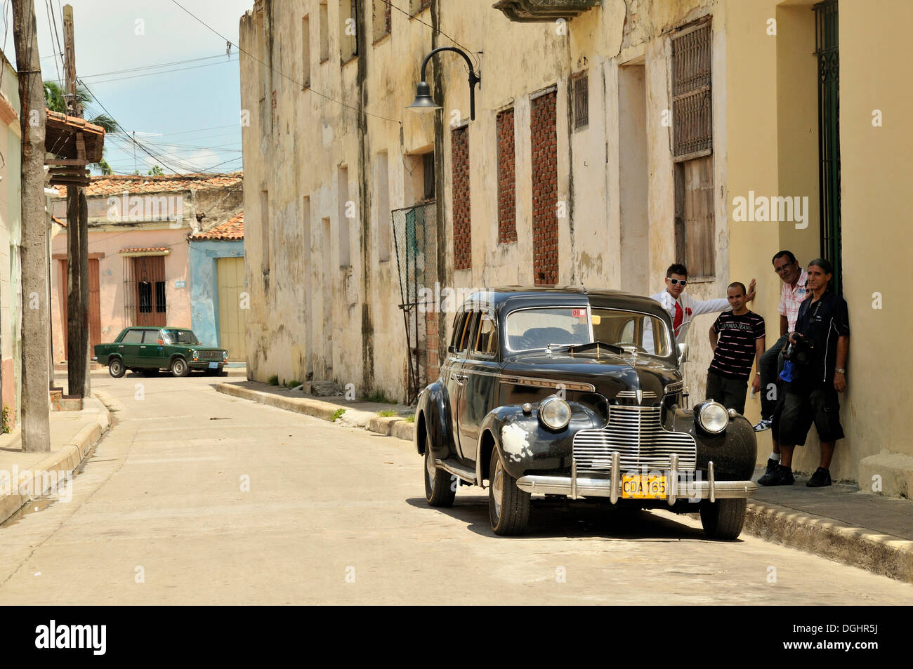 Locals admire a classic car in the historic town of Camagueey, Cuba, Caribbean Stock Photo