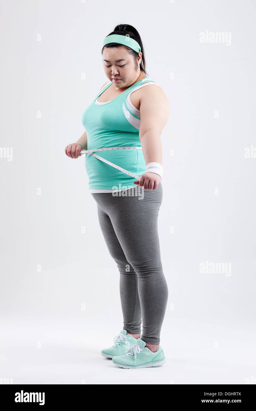 a fat girl in a gym outfit measuring herself Stock Photo Alamy