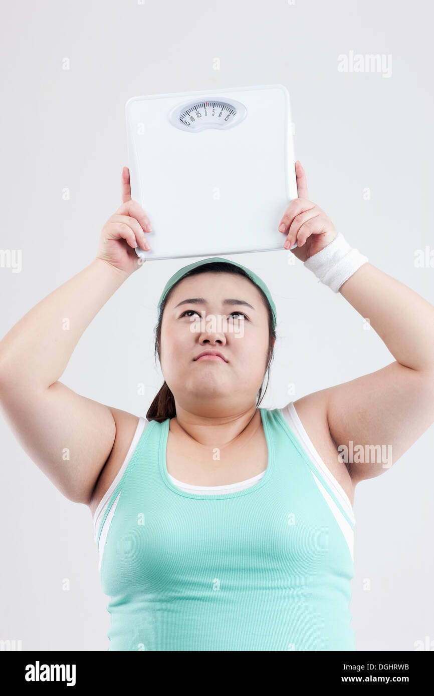a fat girl in a gym outfit holding a weight scale Stock Photo Alamy