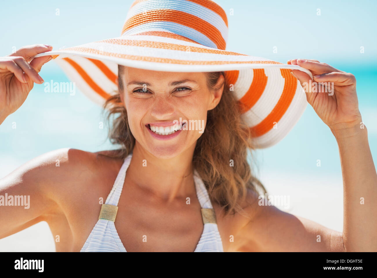 Portrait of smiling young woman in swimsuit and beach hat Stock Photo