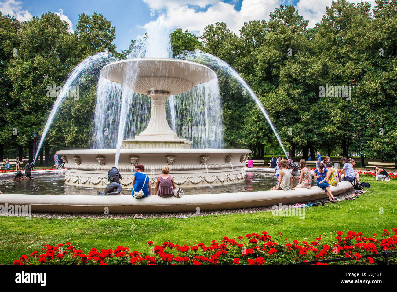 People cooling off round the fountain in Ogrod Saski which is the oldest public park in Warsaw. Stock Photo