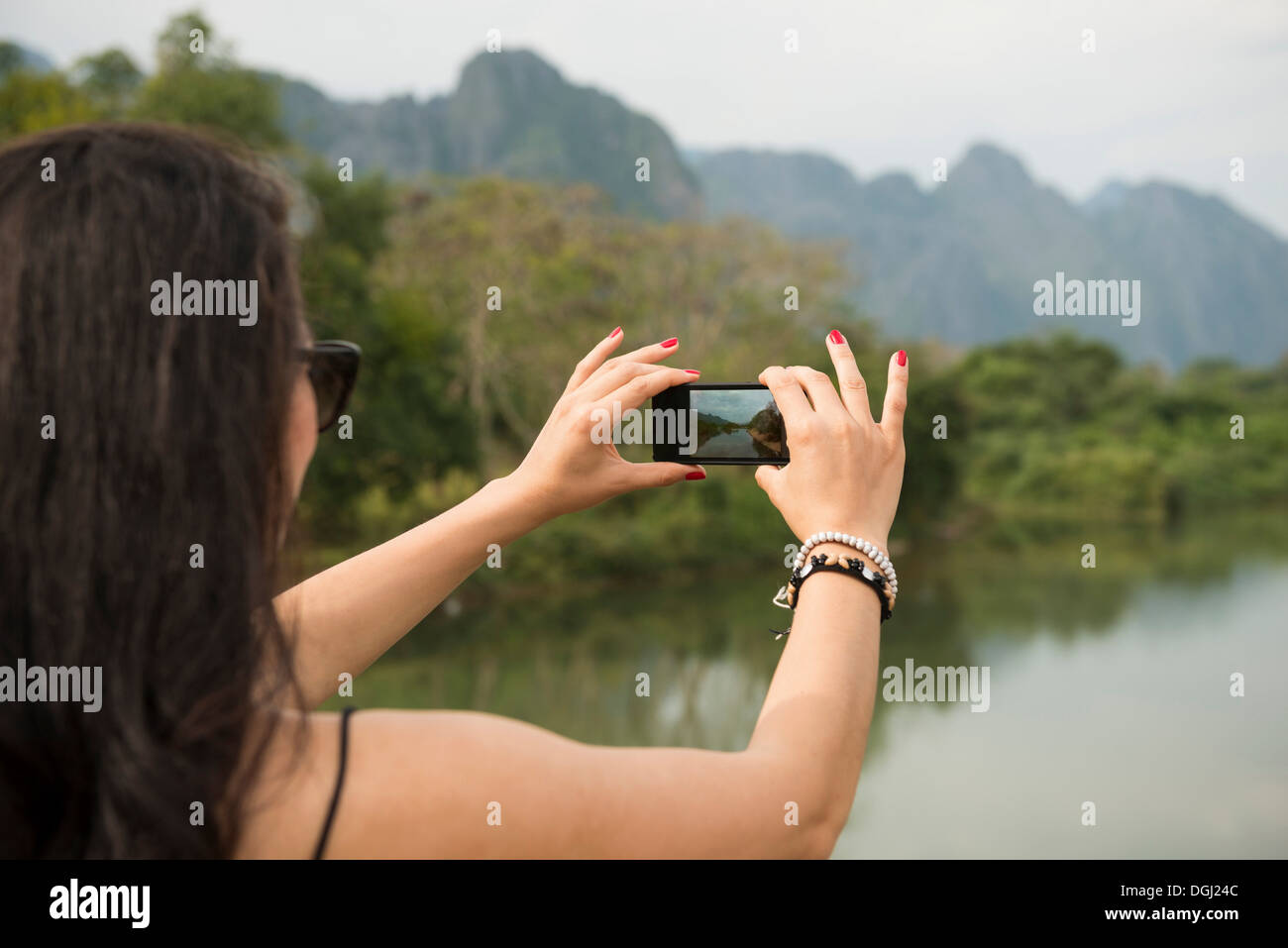 Woman using camera phone, Nam Song River, Vang Vieng, Laos Stock Photo