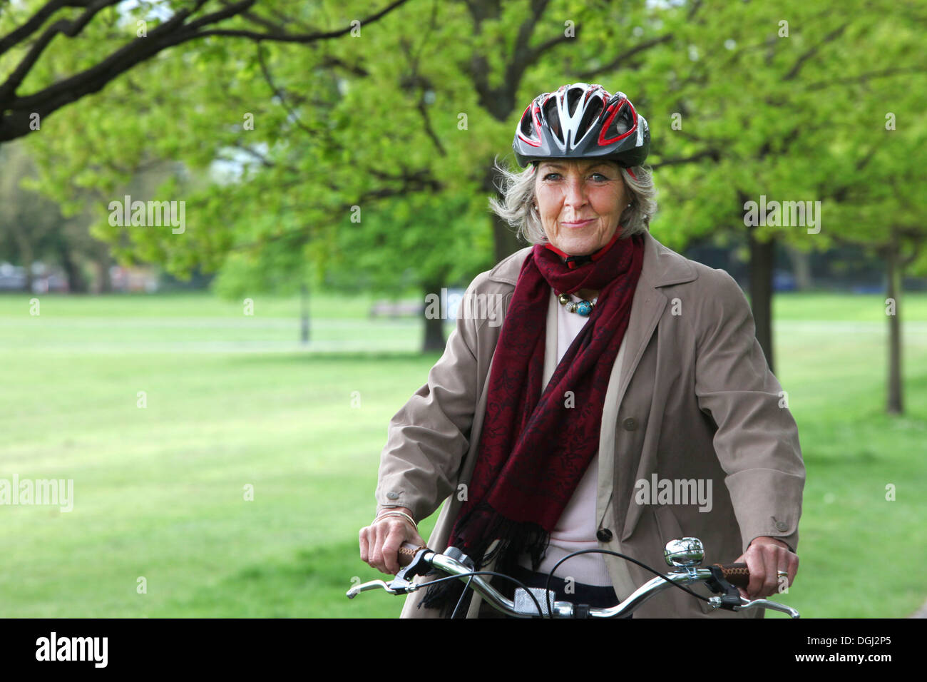 Senior woman riding bicycle in park, portrait Stock Photo