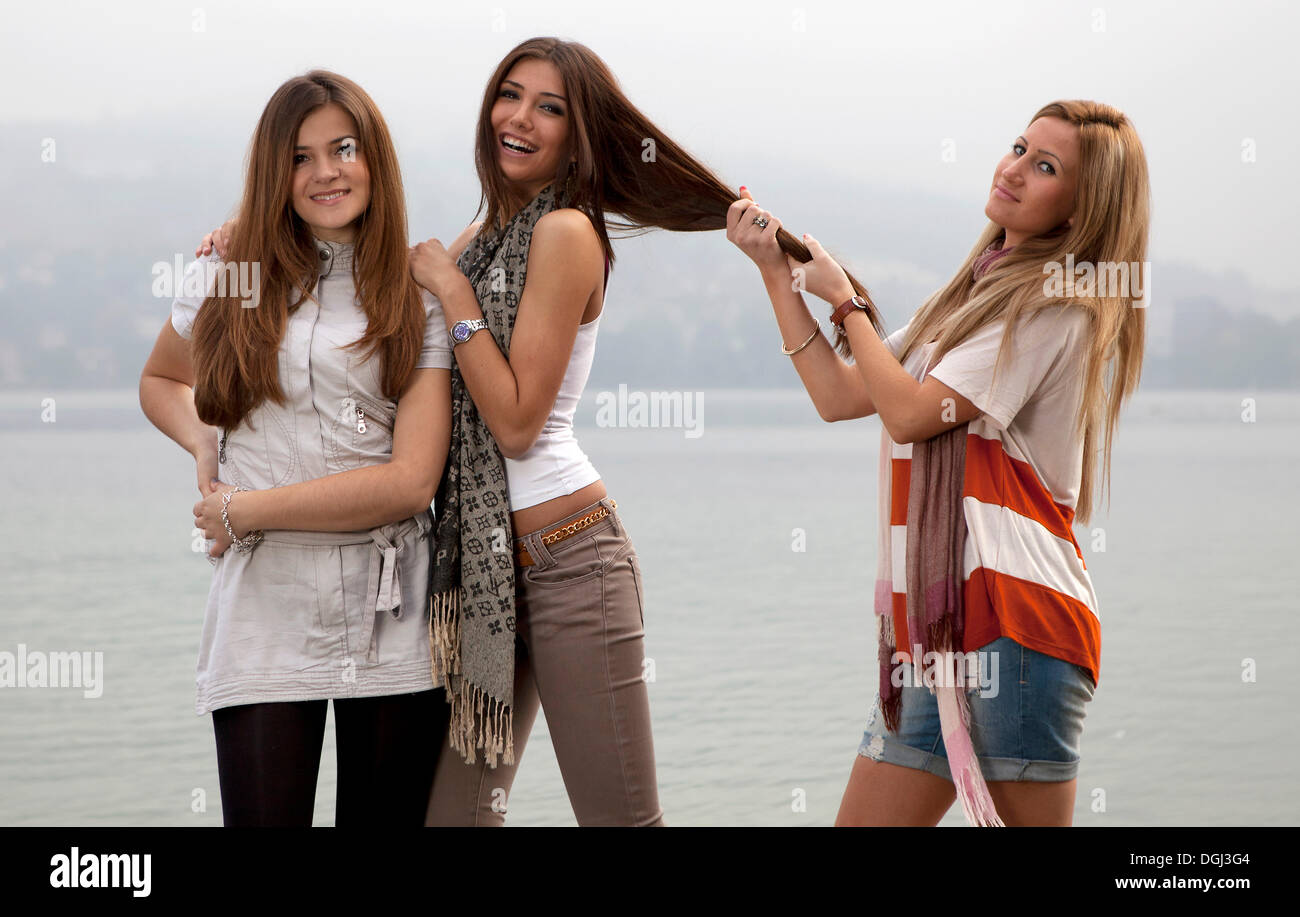 Three young women with long hair posing on a beach Stock Photo