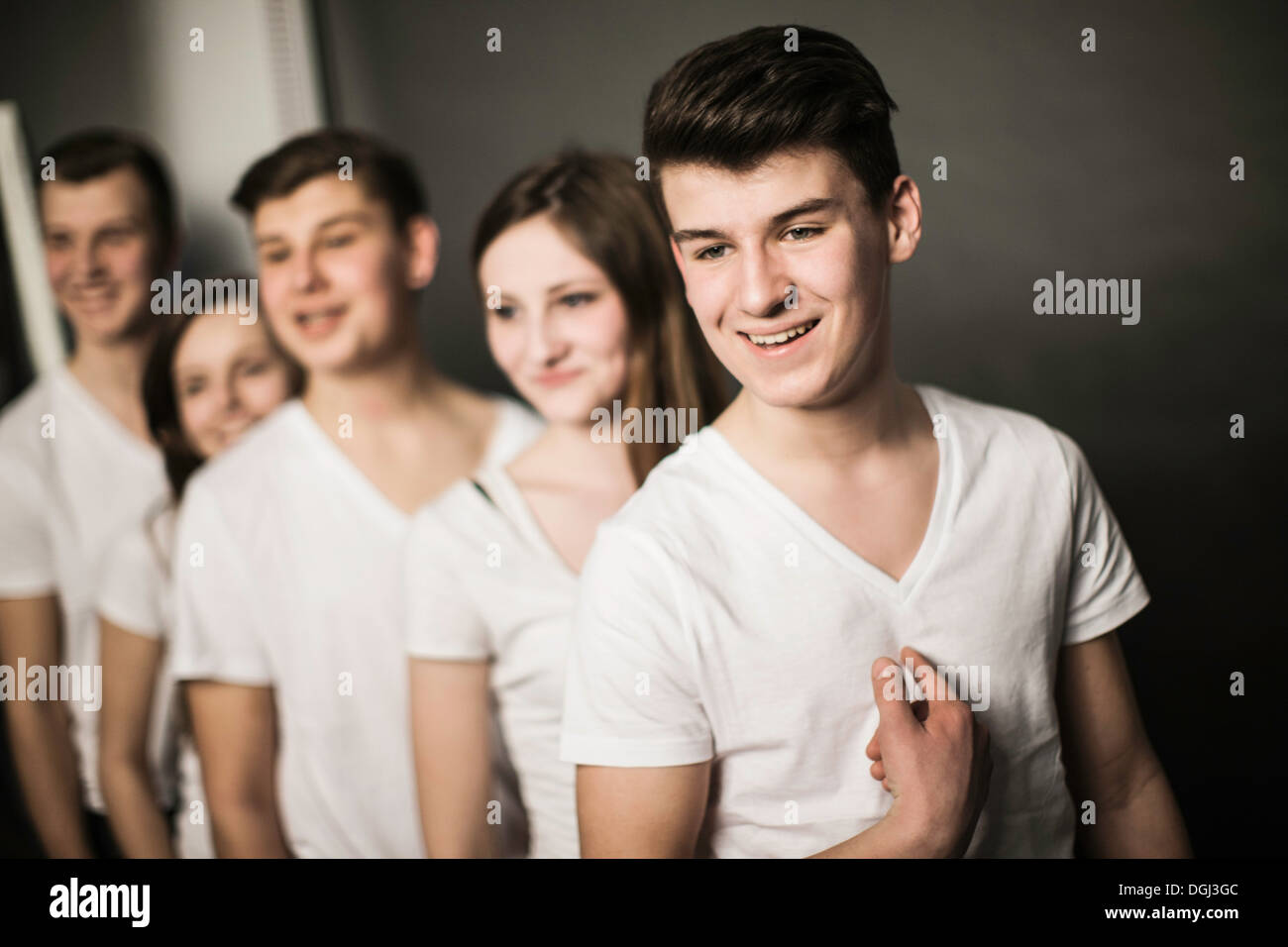 Five teenagers standing in row, all wearing white color top garments Stock Photo