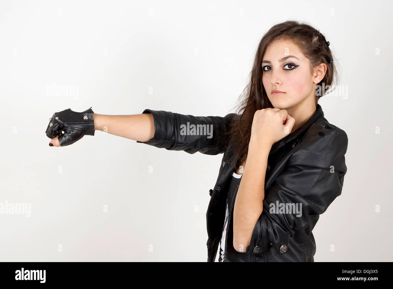 Young woman wearing a leather jacket with her fists held up in a challenge Stock Photo