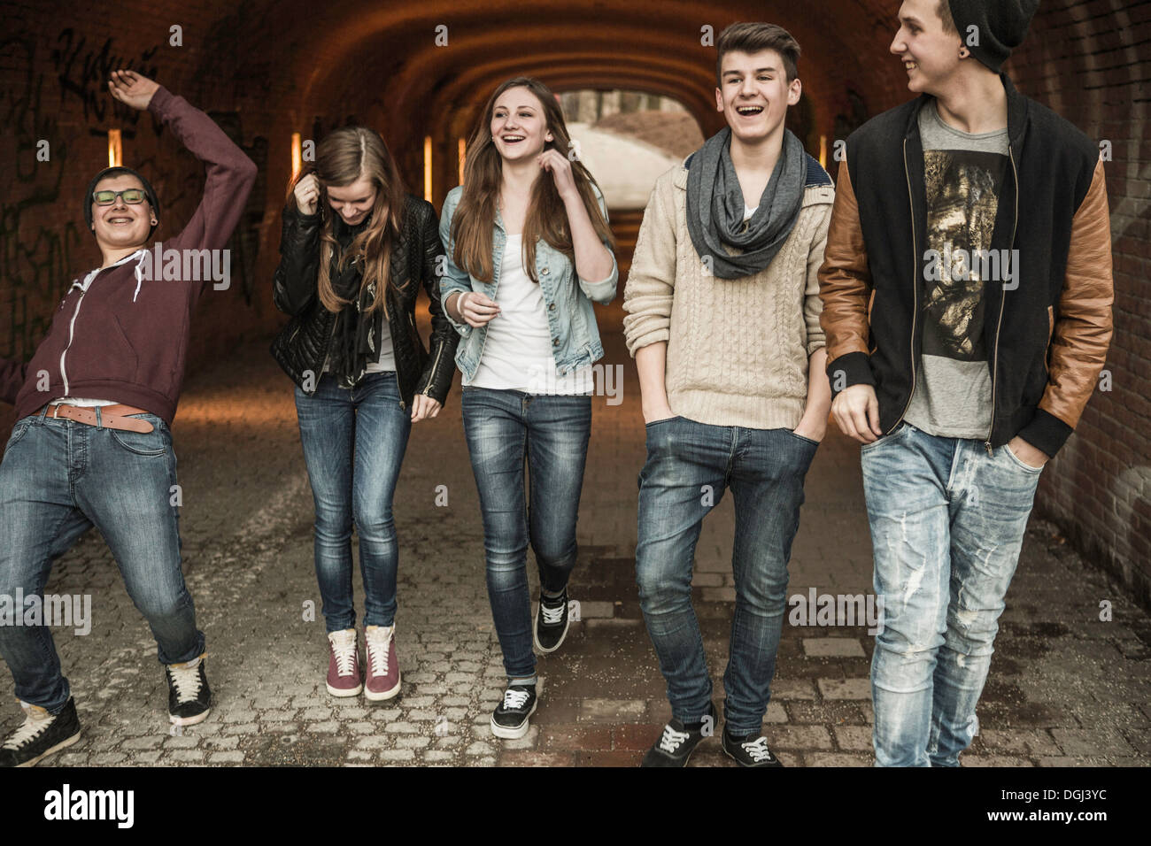Five teenagers walking through tunnel laughing and joking Stock Photo