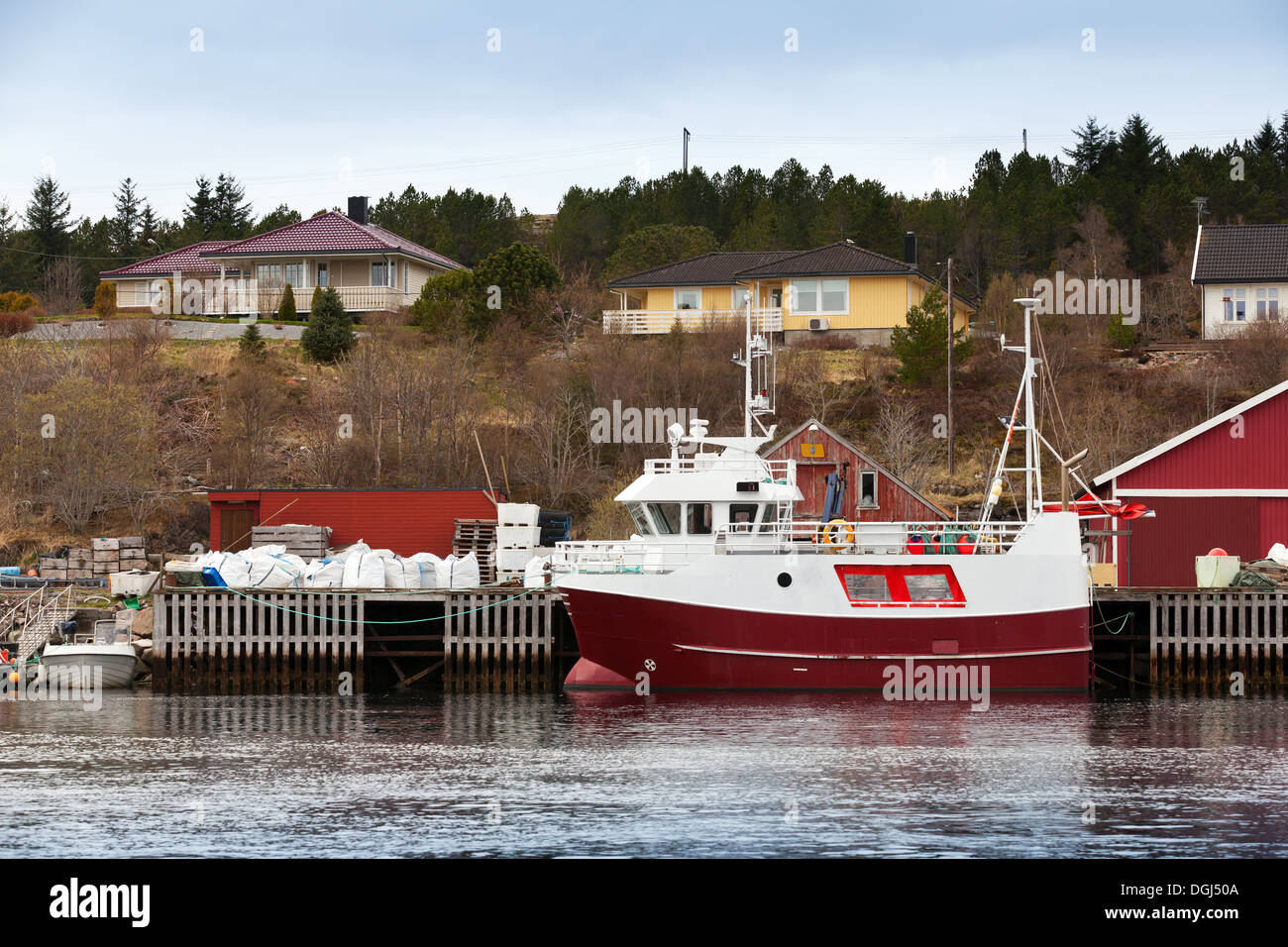 Small red and white fishing boat stands moored in Norway coastal town Stock Photo