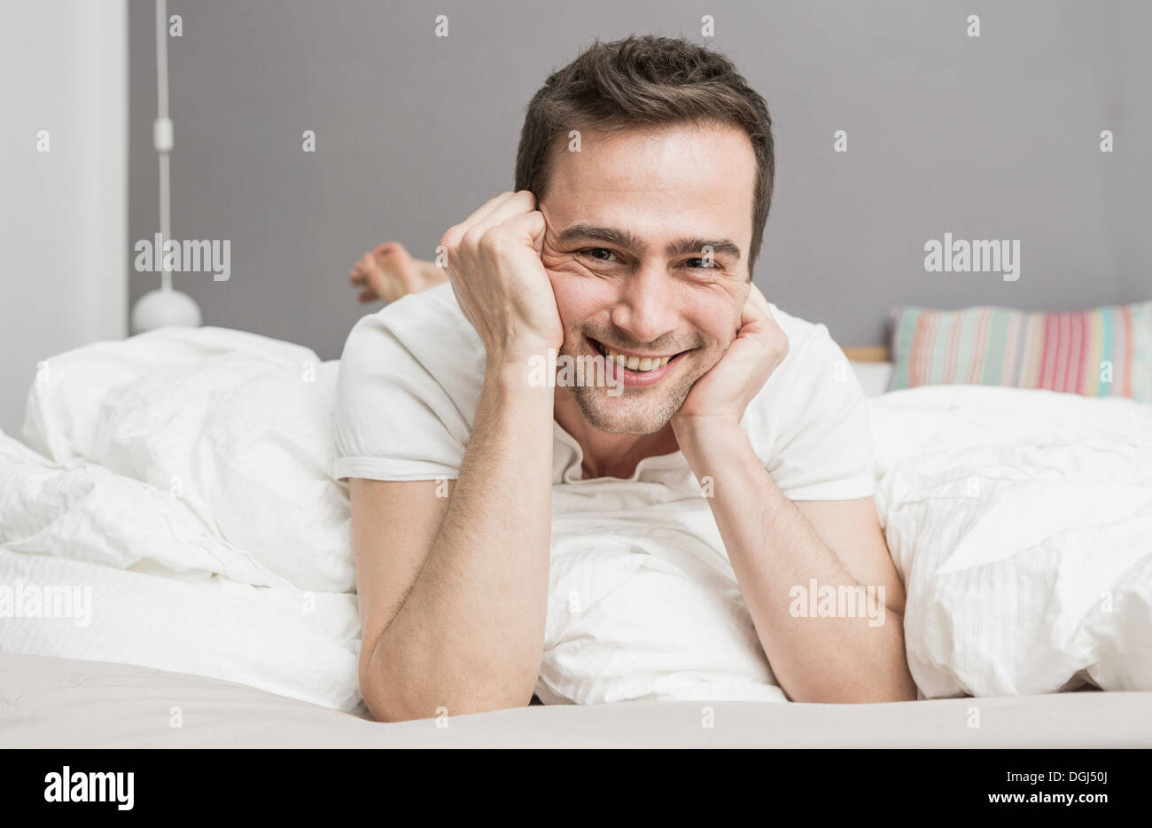 Mid adult man lying on front on bed Stock Photo