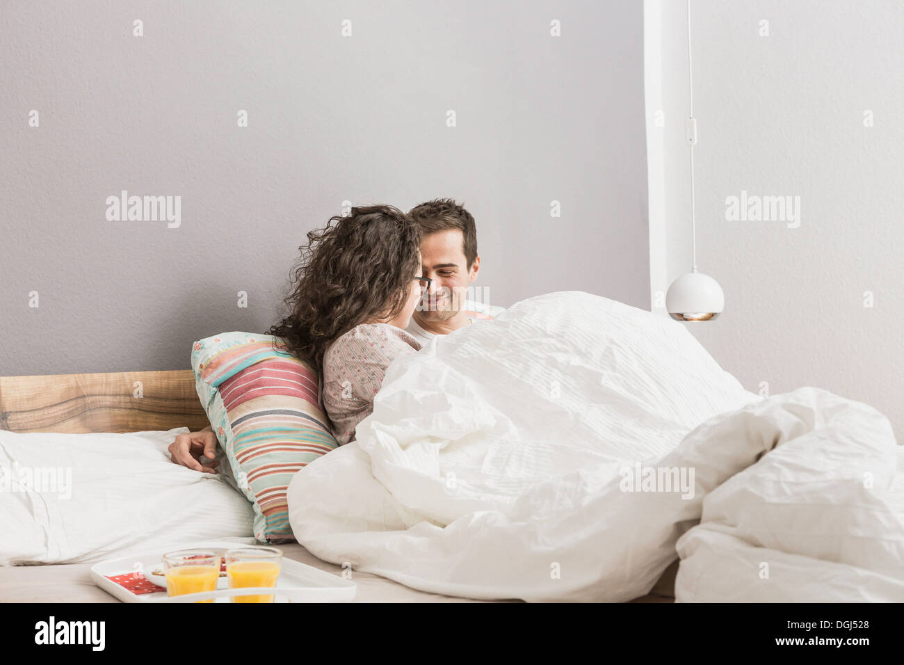Mid adult couple lying in bed, breakfast on tray Stock Photo