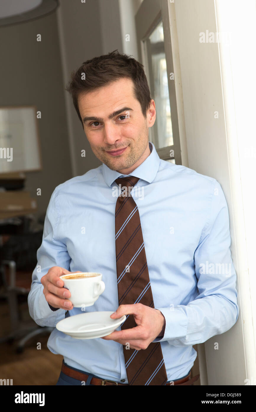 Mature man wearing shirt and tie holding cup of coffee Stock Photo