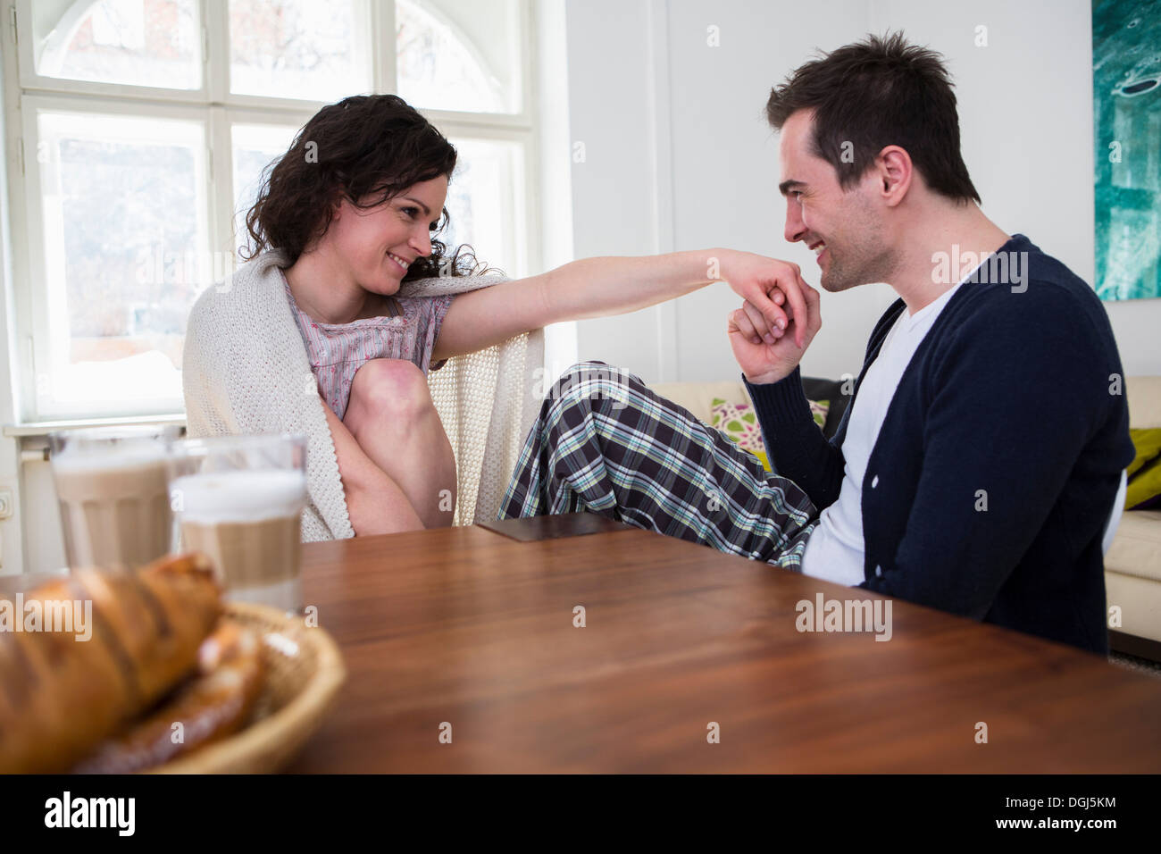 Heterosexual couple holding hands at breakfast table Stock Photo