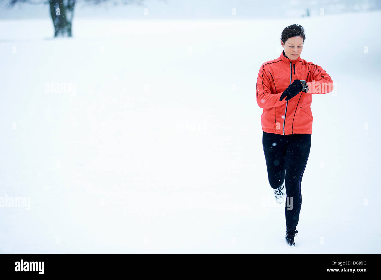 Woman timing her snow running Stock Photo