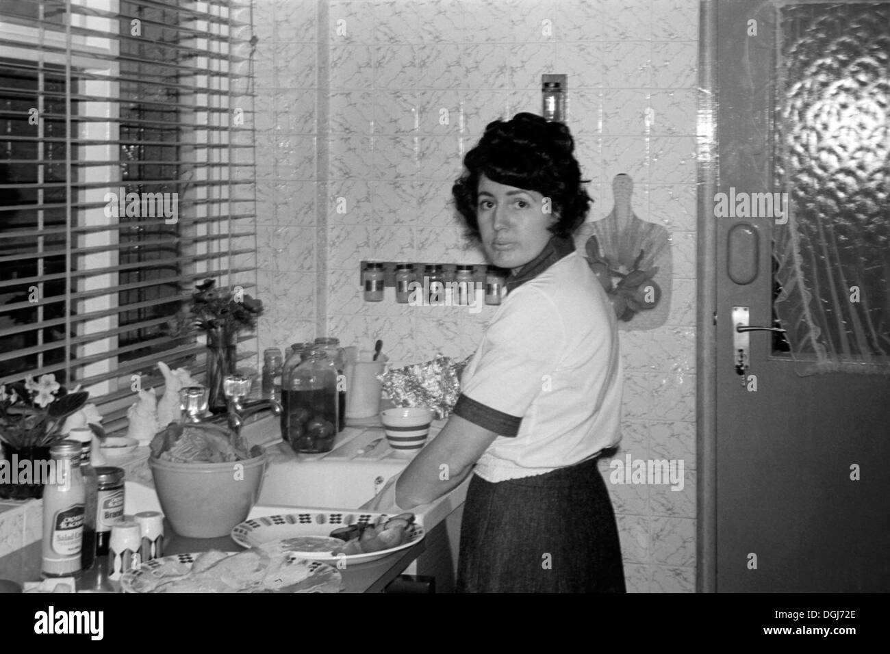 housewife washing dishes in kitchen after christmas day supper uk 1970s Stock Photo