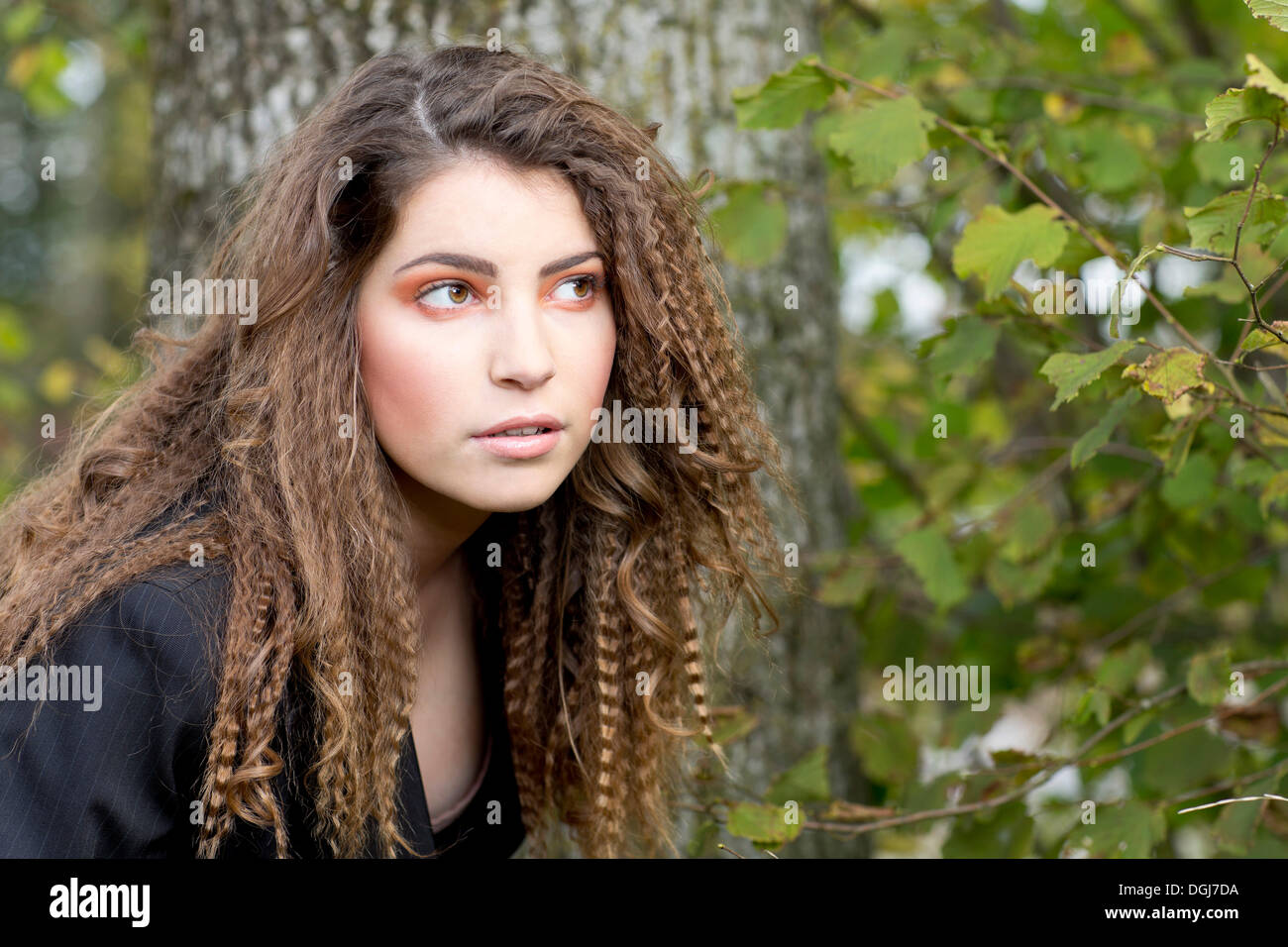 Young woman with long hair in front of a tree, portrait Stock Photo