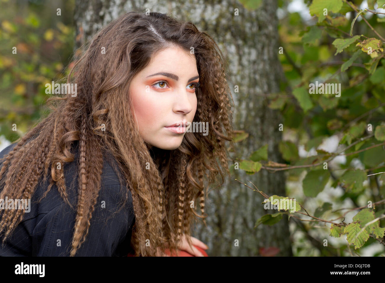 Young woman with long hair in front of a tree, portrait Stock Photo