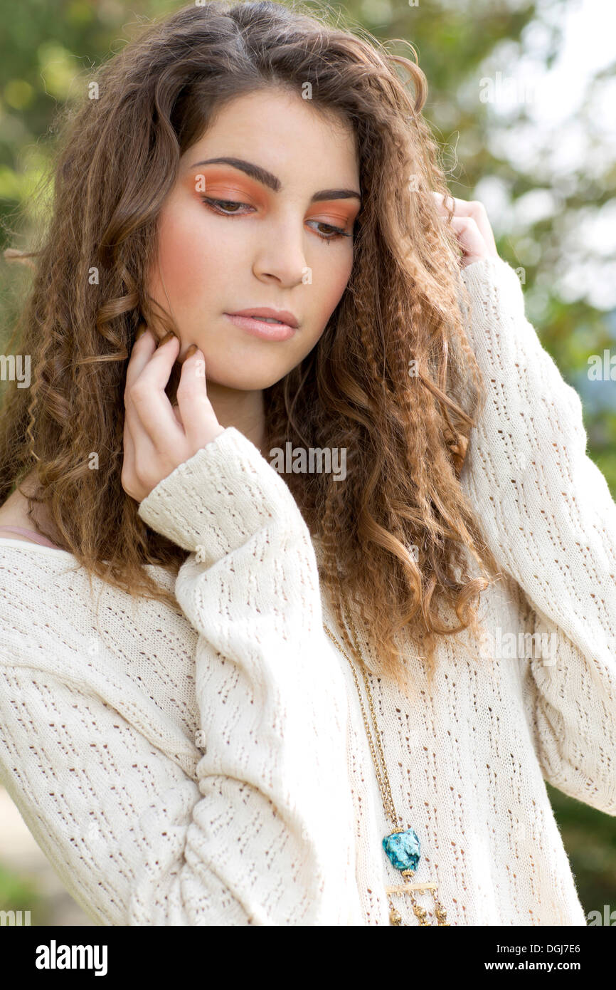 Young woman wearing a white sweater, outdoors Stock Photo