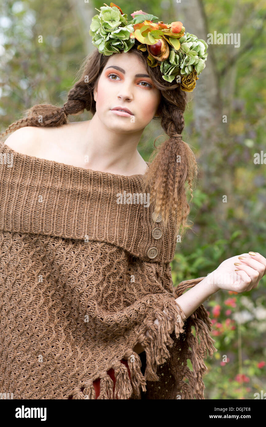 Young woman wearing a brown poncho with a flowal wreath in her hair, outdoors Stock Photo
