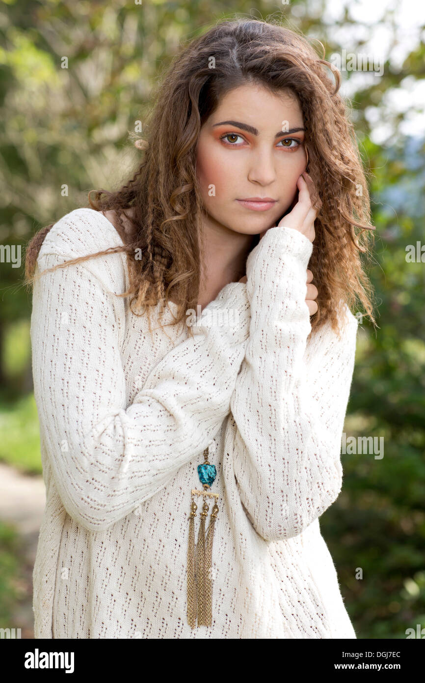 Young woman wearing a white sweater, outdoors Stock Photo