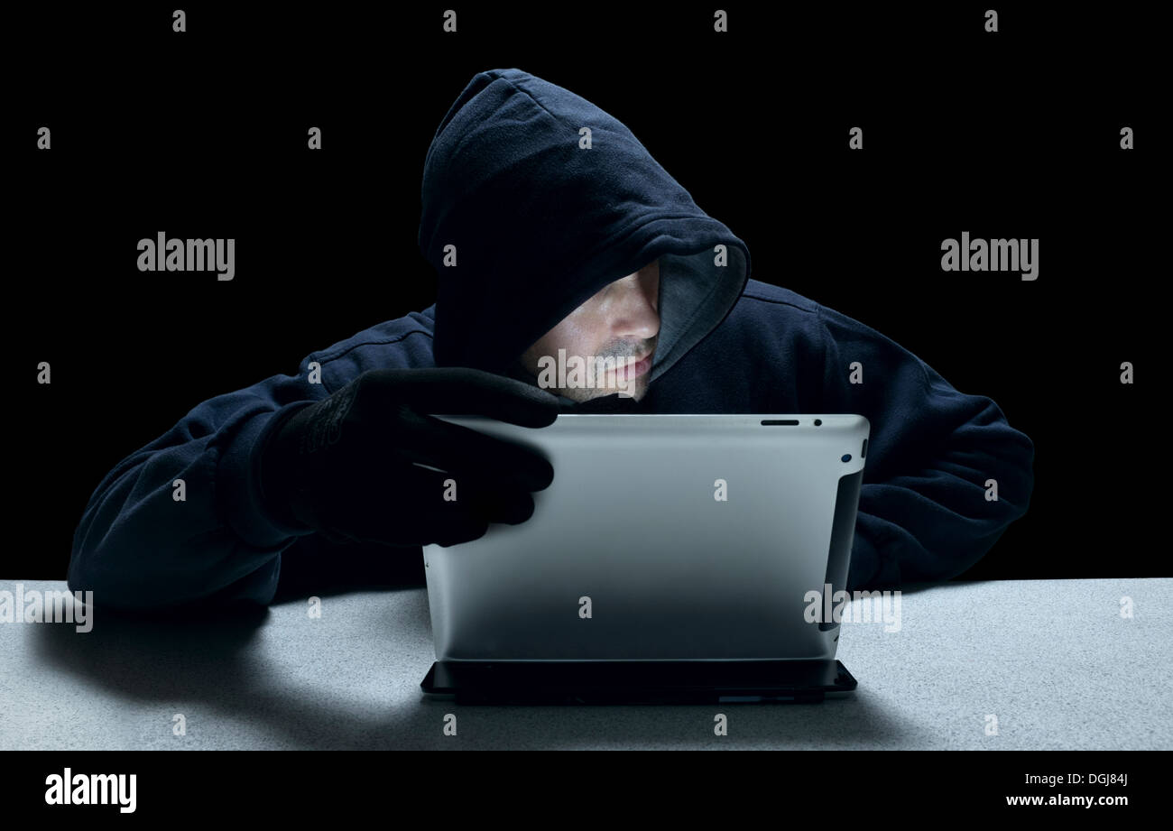 A hooded man representing a cyber criminal. Stock Photo