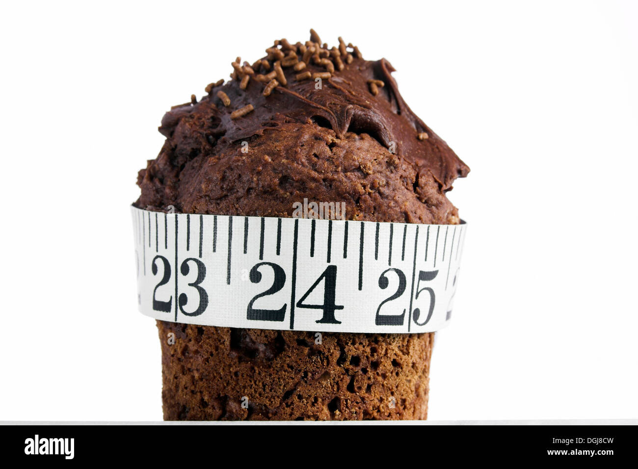 Chocolate cake with a measuring tape wrapped around it signifying weight gain. Stock Photo