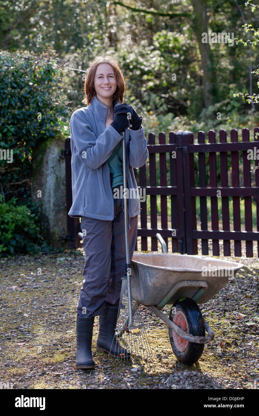 Young woman with a wheelabarrow and garden rake. Stock Photo