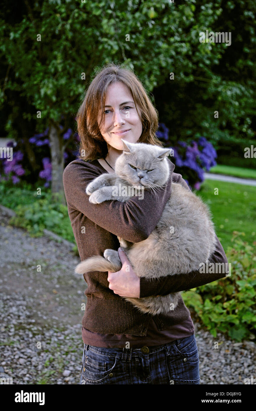 Young woman with a grey cat in her arms. Stock Photo