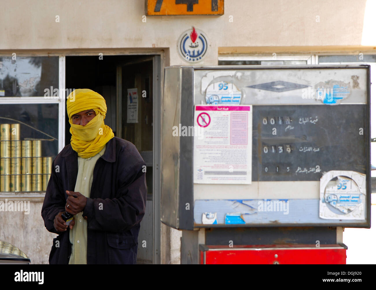Arab gas station operator with a yellow turban next to a petrol pump at a gas station, Germa, Libya, Africa Stock Photo