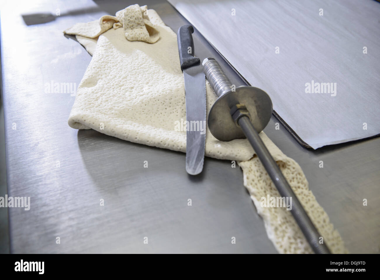 Offcut of dough, knife and rolling instrument in bakery Stock Photo