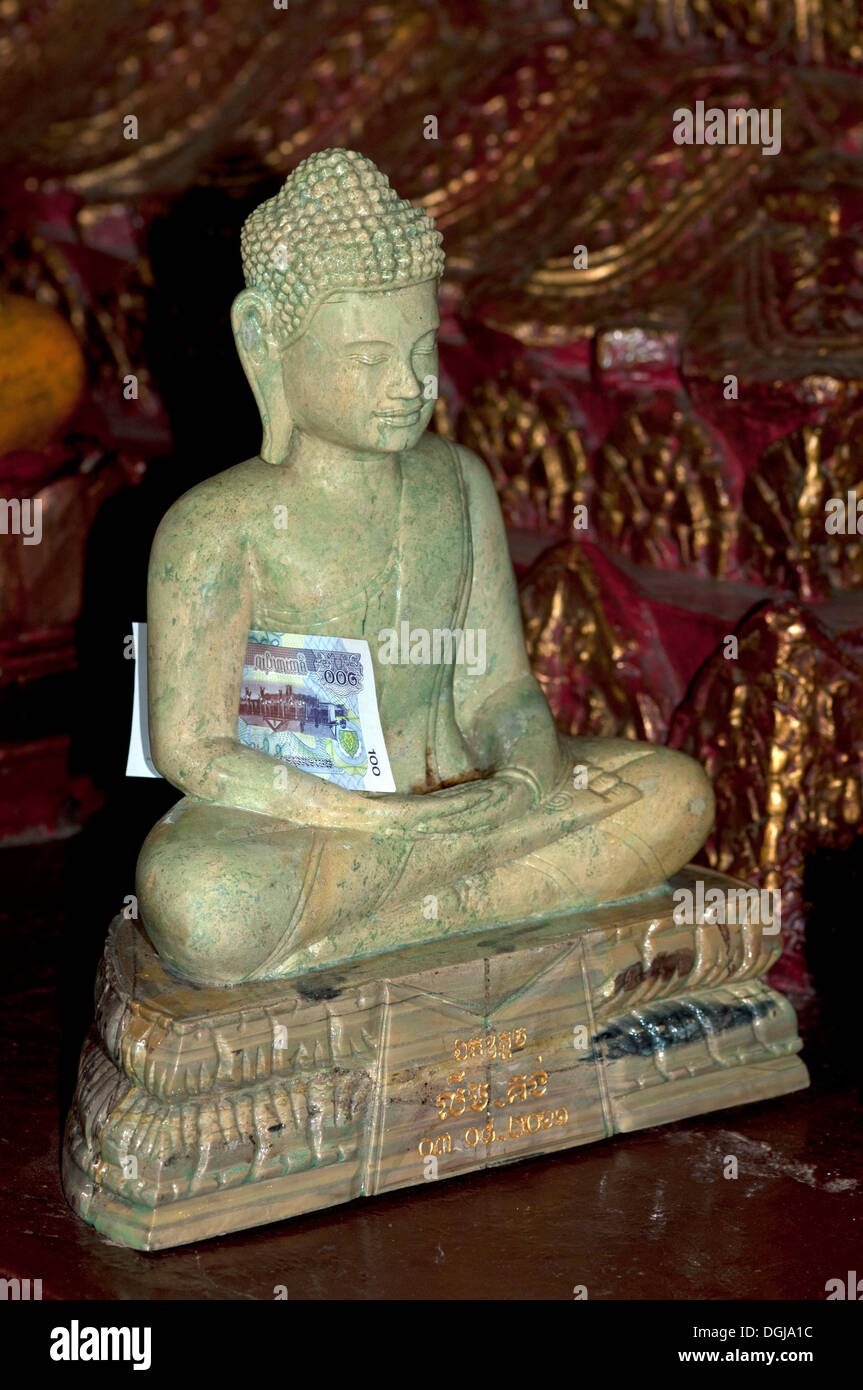 Buddha statue made of marble with a banknote as an offering inside the
