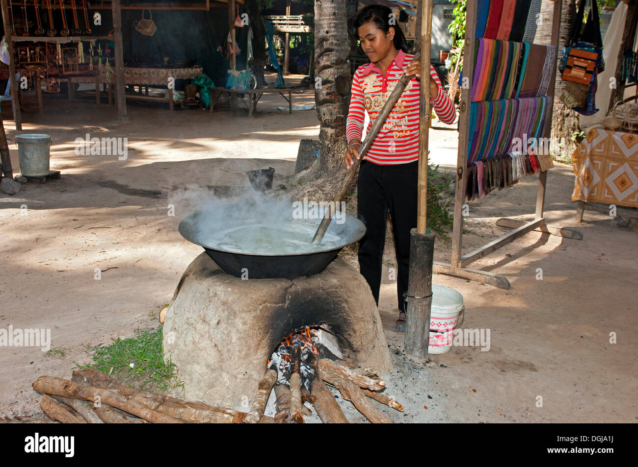 Khmer woman stirring palm sap in a traditional heated metal boiler to produce palm sugar, Siem Reap, Cambodia, Southeast Asia Stock Photo